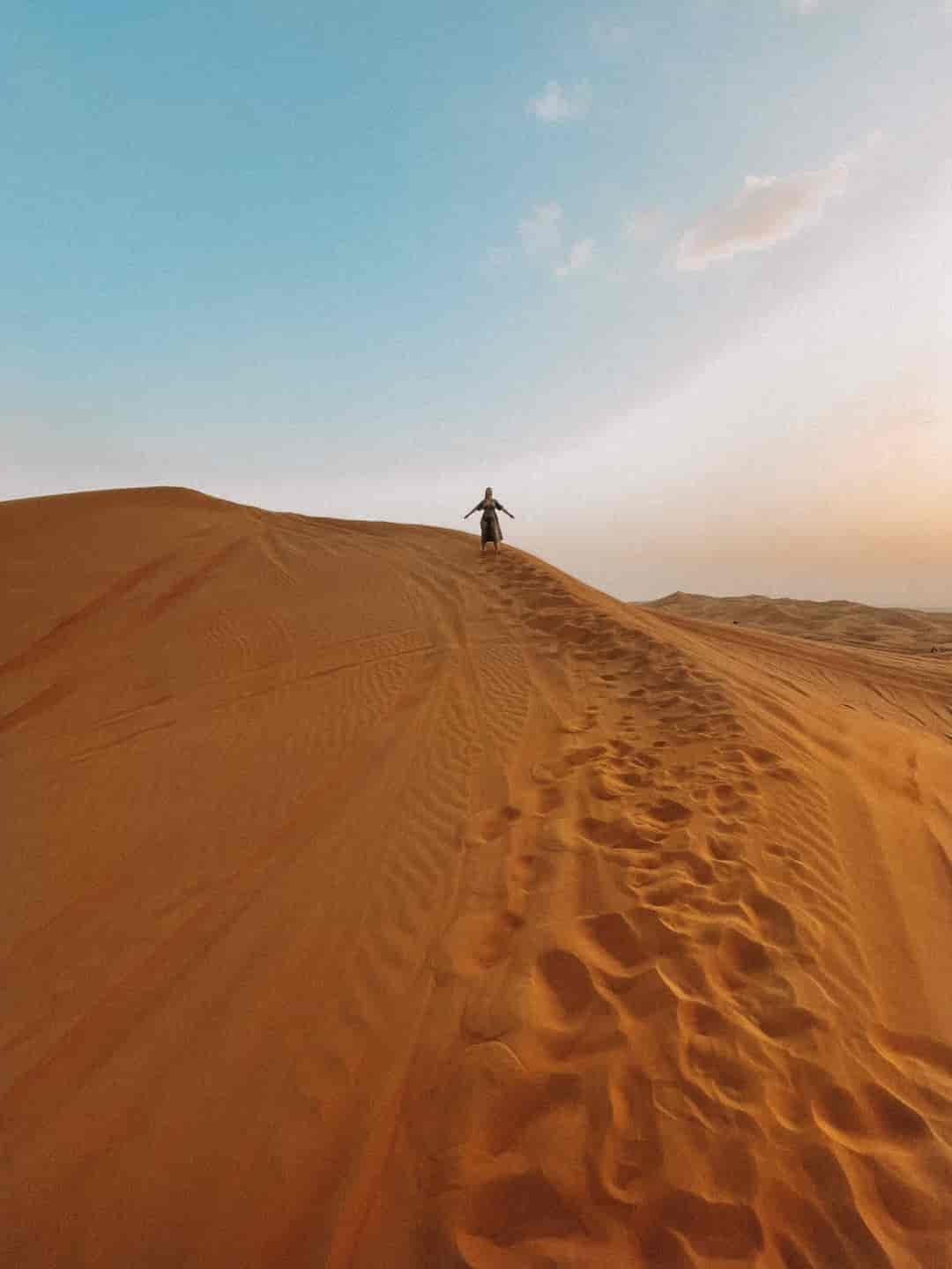 Image d'une femme sur une dune dans le désert à Dubaï