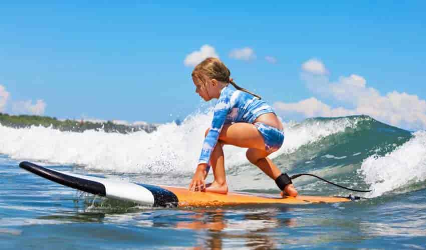 Jeune fille surfant avec joie sur les vagues