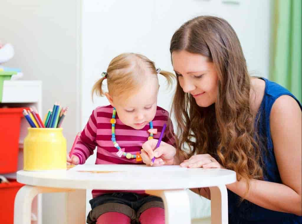 Une nounou et une fillette dessinant sur une table