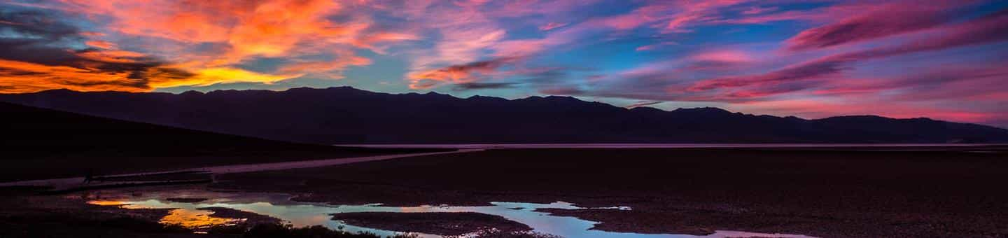 colorful sunset over wide landscape of mountains and small pool of waterDeath Valley Sunset