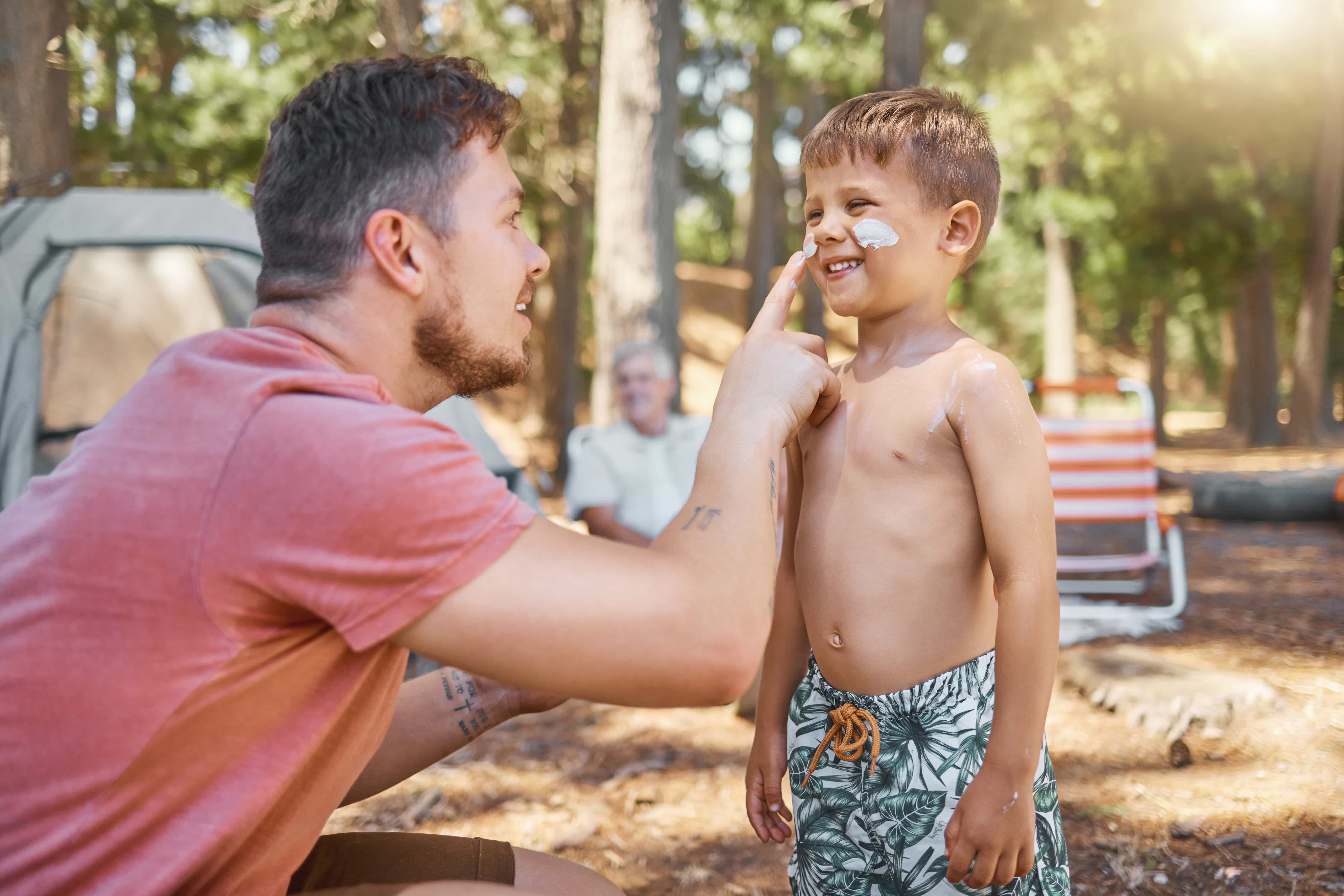 Father applying sunscreen to young boy.