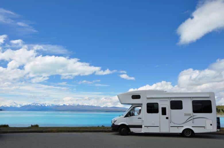 Un camping-car sur la route devant un beau paysage avec un lac