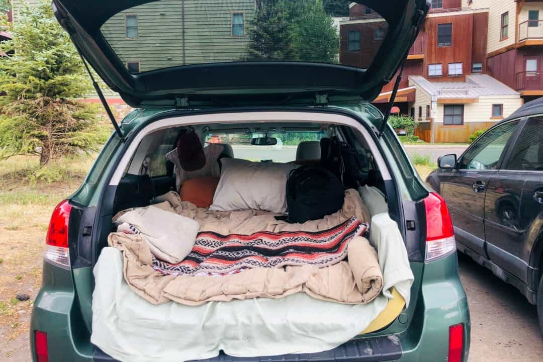 Une voiture avec son coffre ouvert et un lit installé à l'arrière