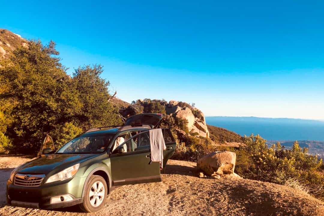 Une voiture verte à hayon ouvert est garée surplombant une montagne pittoresque