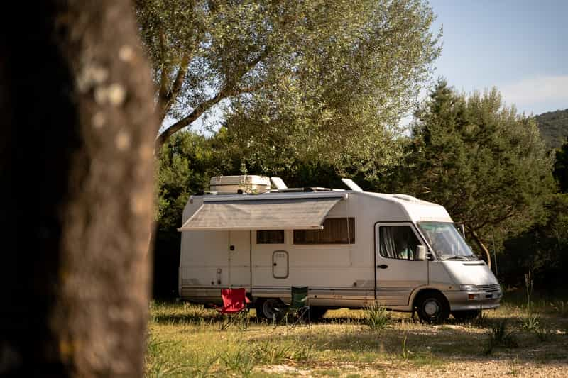 Motorhome parked under trees in shady camping pitch