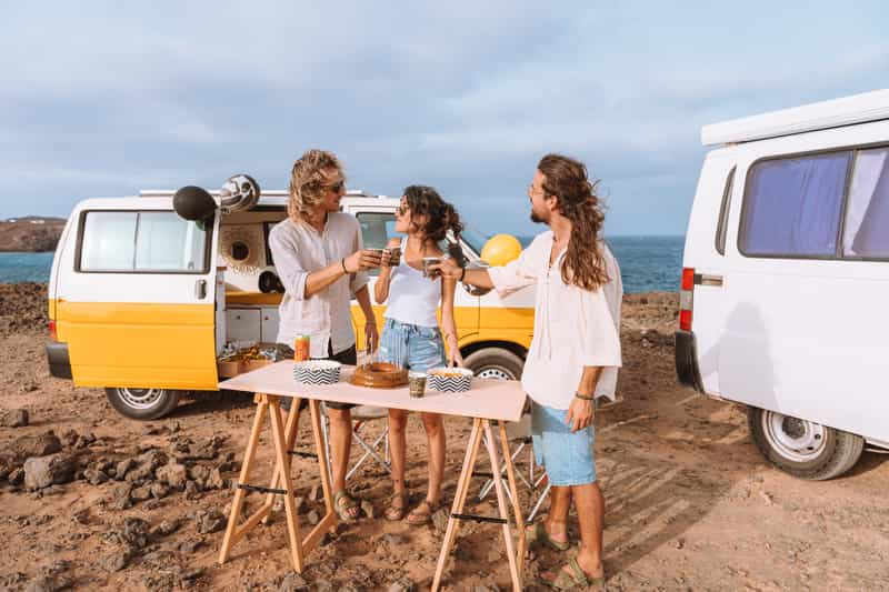 People celebrating in front of campervans