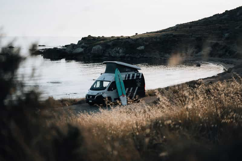 SUP board leading against campervan parked near beach