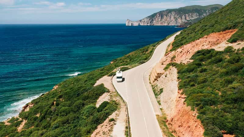 Campervan driving along beautiful road on Sardinian coastline