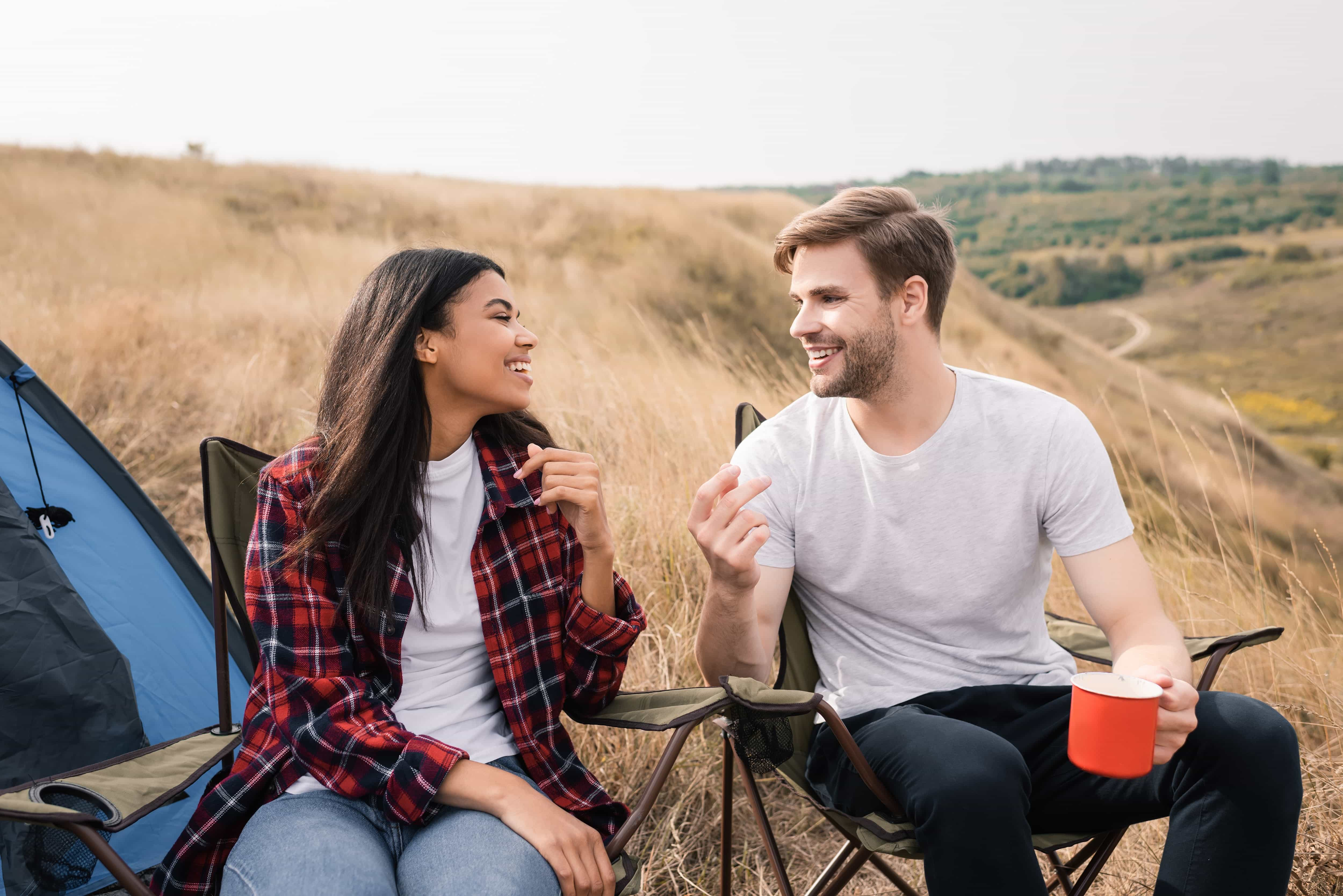 Couple chatting in camping chairs while camping.