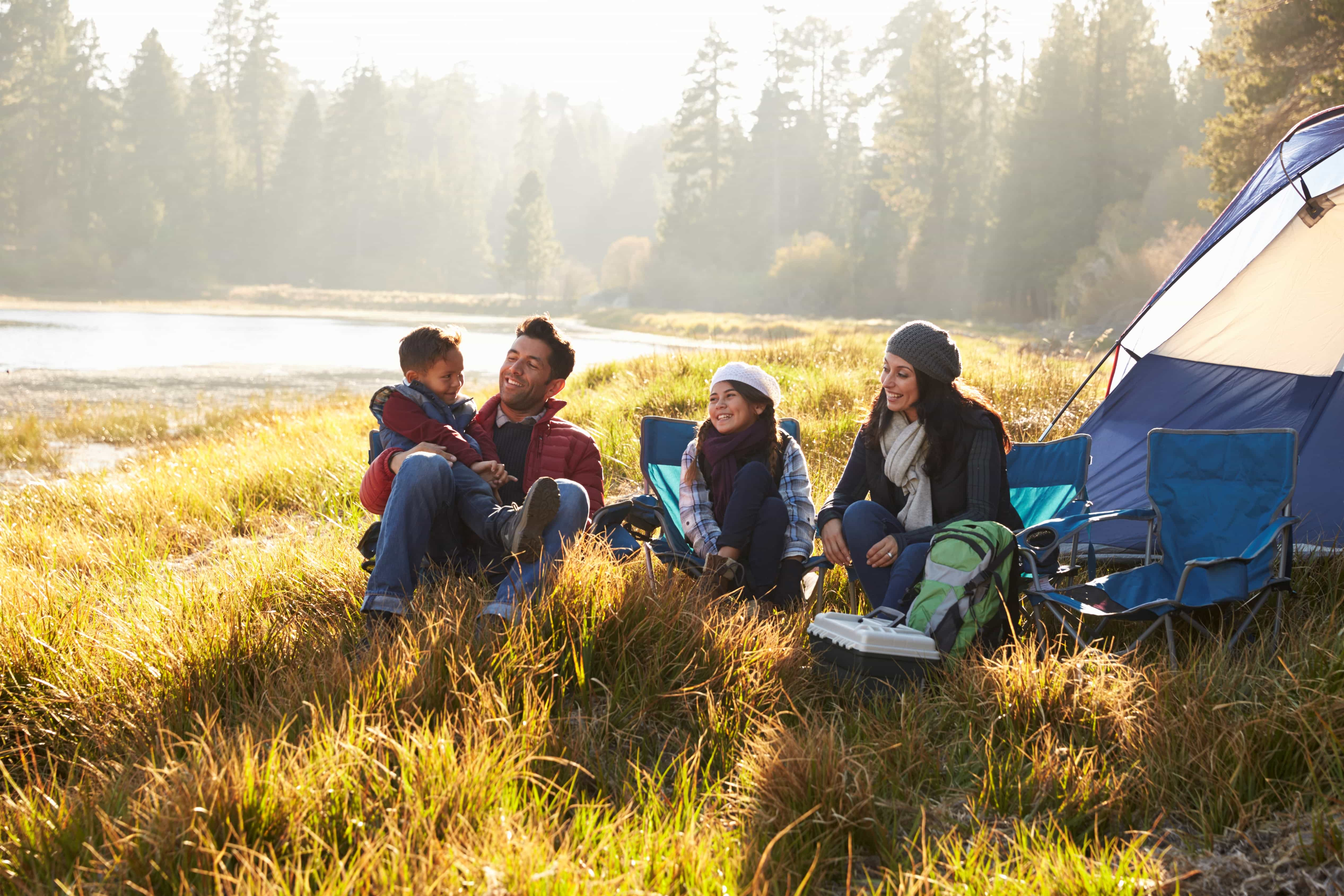 Happy family on a camping trip relaxing by their tent.