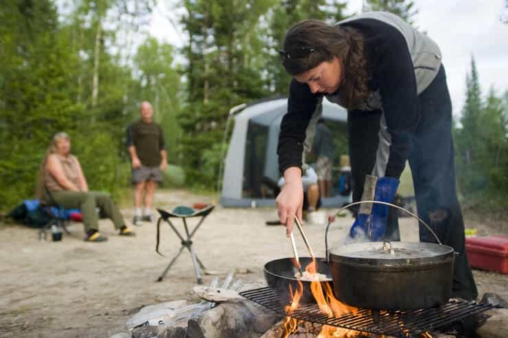 Femme cuisinant autour d'un feu de camp.