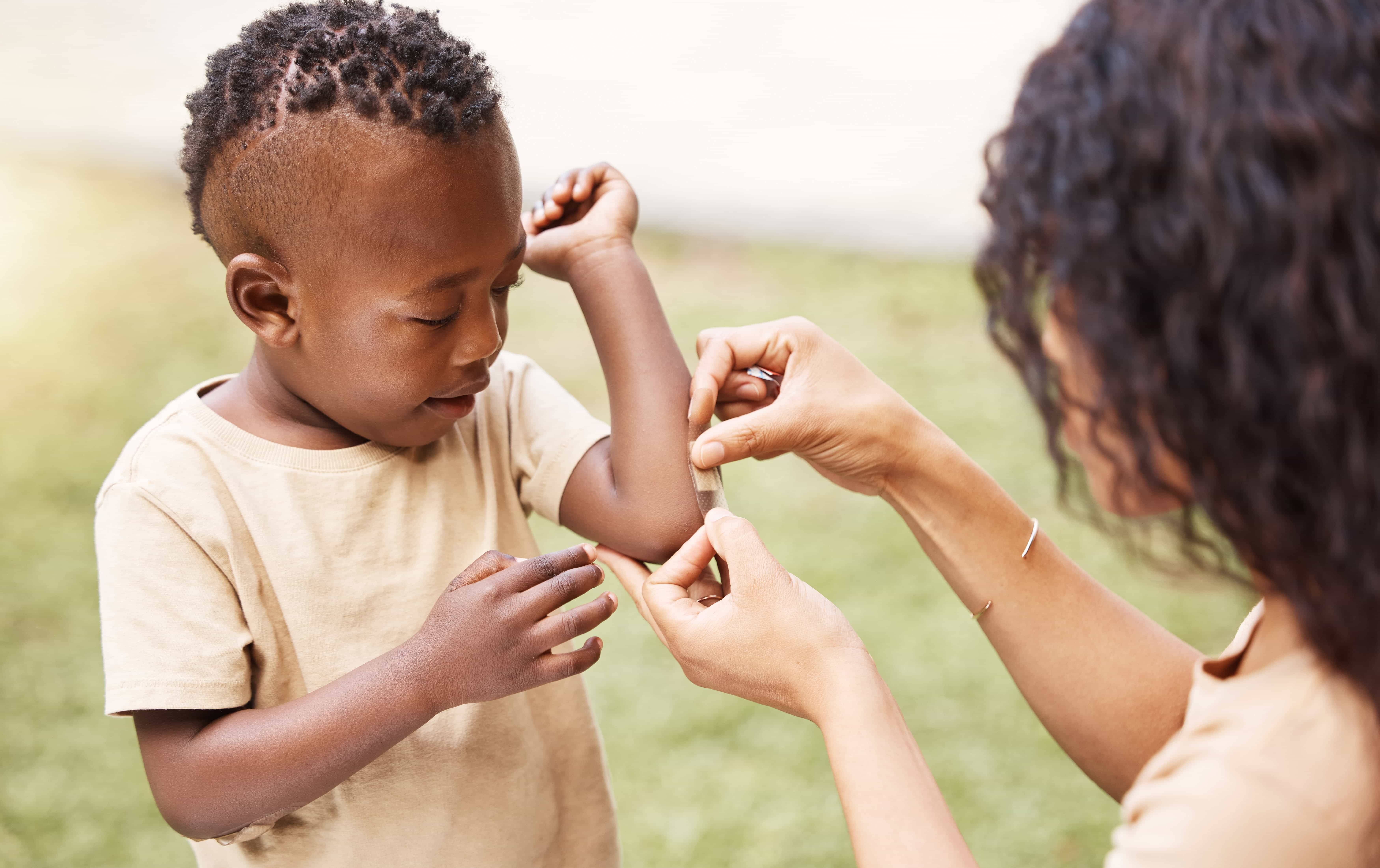 Mother putting a bandaid on a young boy.